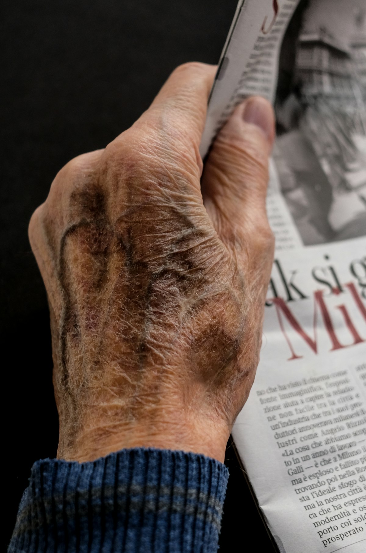 A hand holding a printed newspaper